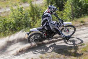 Motocrosser op een Zero XE die een bocht neemt met veel stof op een motorcrossparcours